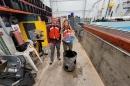 Two 主要研究 student researchers hold their winning ocean renewable energy device in front of a wave tank. They are wearing red life jackets.